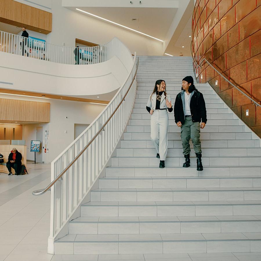 2 Students walk down grand stairs in UHall